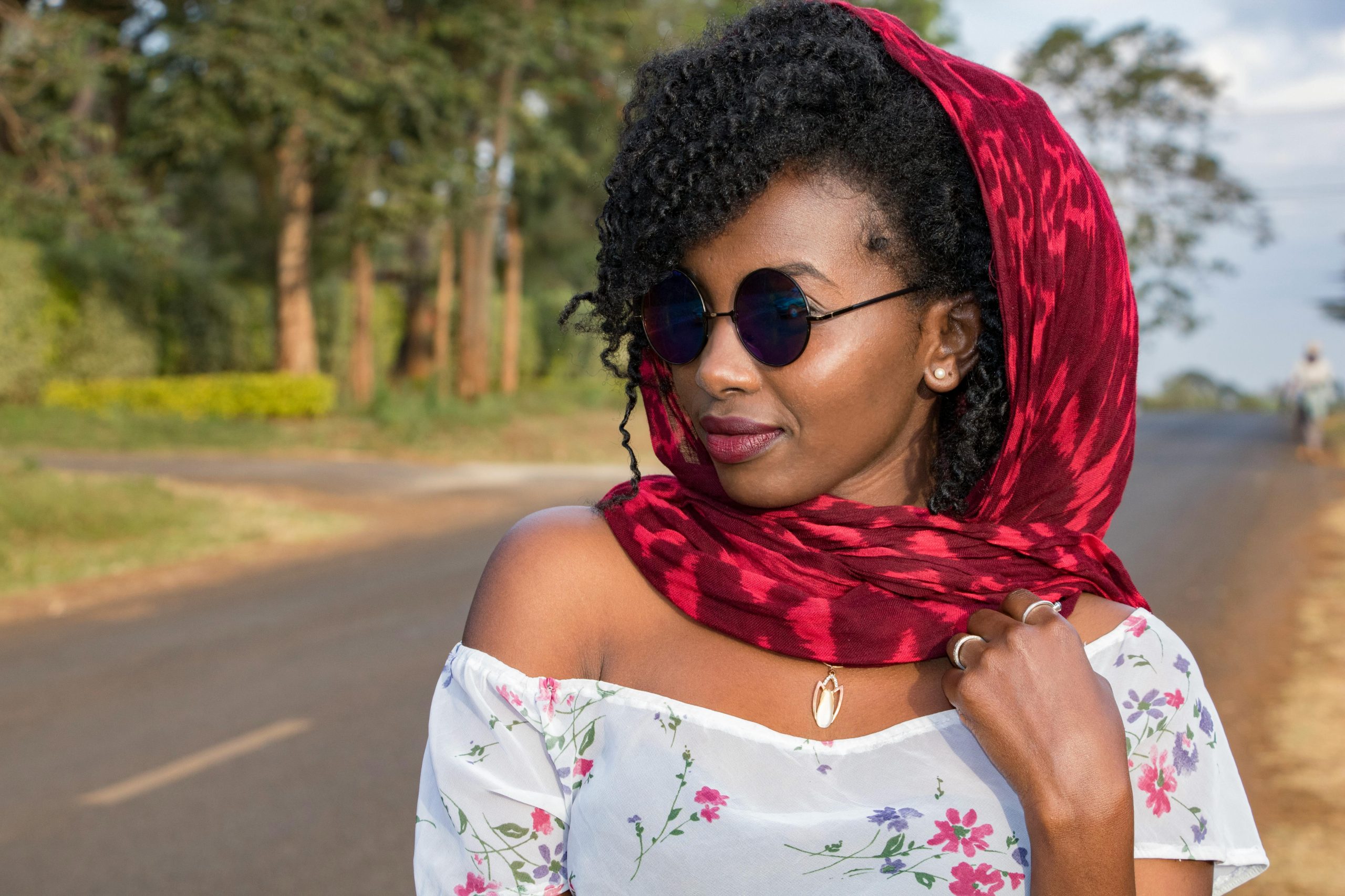 Portrait of a fashionable woman wearing sunglasses and a red scarf outdoors, exuding style and confidence.