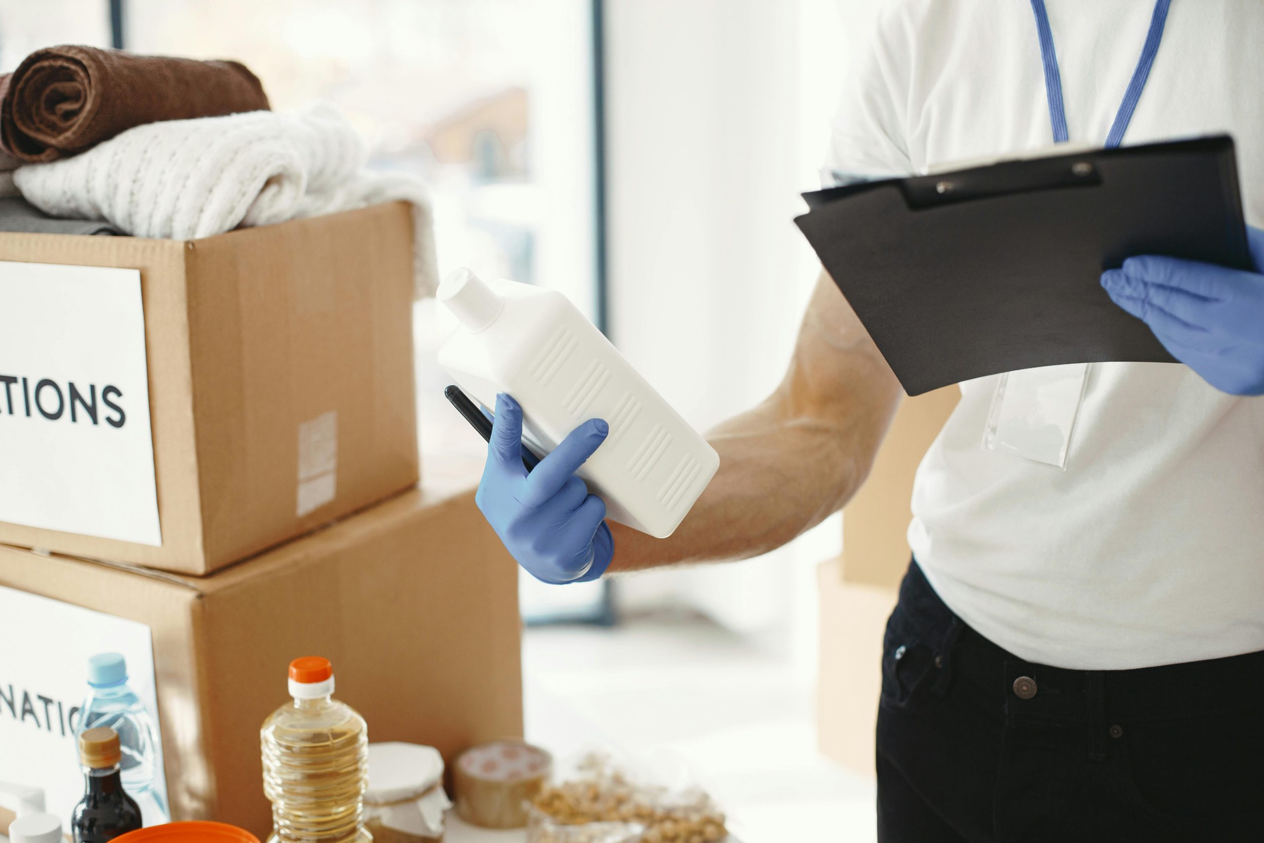 Focused volunteer in gloves sorting donation supplies in a community center.